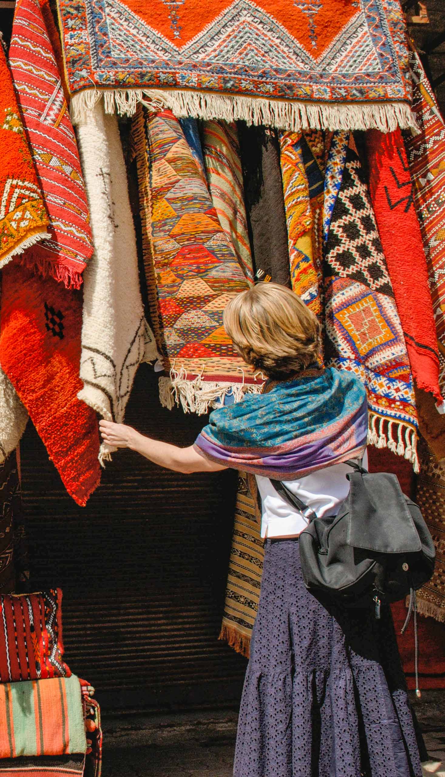 A tourist browsing through rugs in a market in Marrakech.
