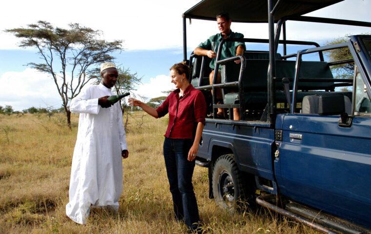 Two travelers being served wine on a safari in Tanzania.
