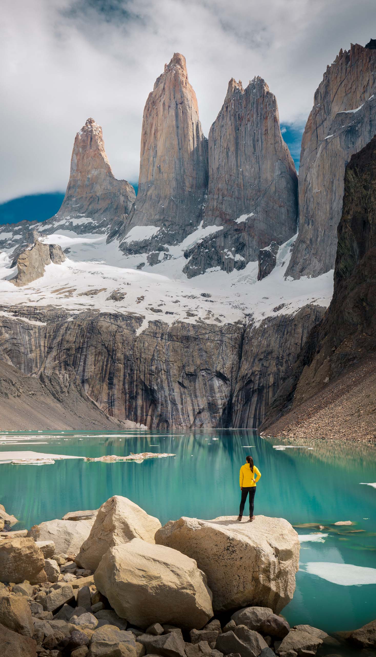 Woman standing on the rock in front of the stunning Torres del Paine peaks.
