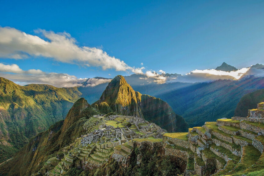 View of Machu Picchu, an ancient Incan citadel in the Andes Mountains, with surrounding lush green mountains and a clear blue sky—perfect for those who love REI Adventure trips.