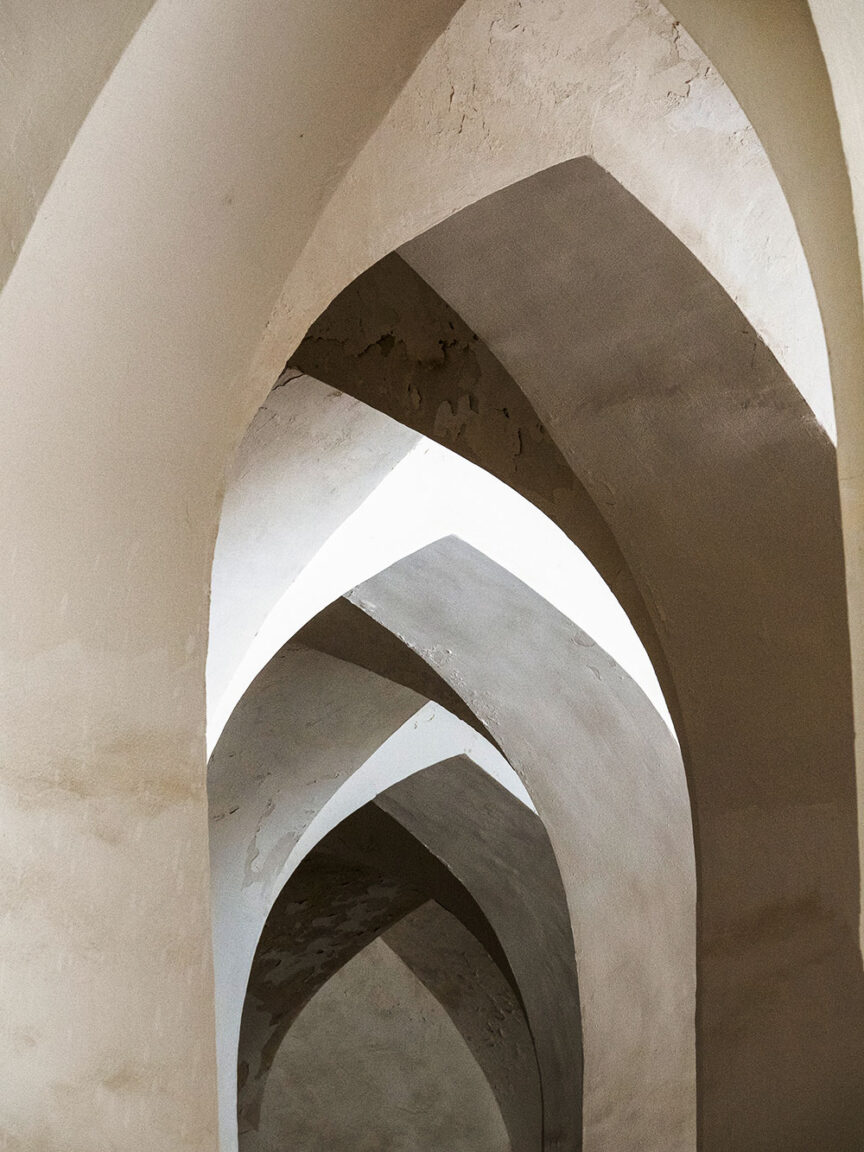 Arched stone ceiling with multiple intersecting, pointed arches creating a geometric pattern, reminiscent of the architectural marvels encountered on a Silk Road cultural journey, illuminated by light from above.