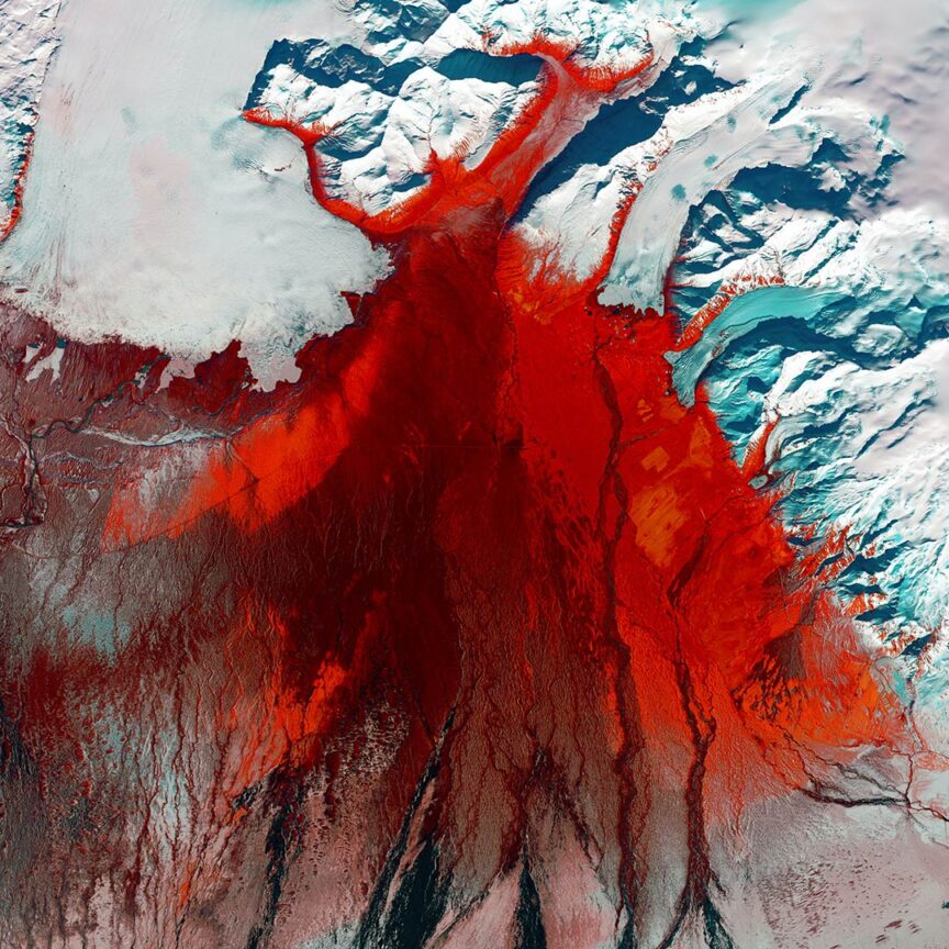 A stunning satellite image shows a red-stained glacier landscape with white snow and ice, depicting a dramatic visual contrast on Earth.