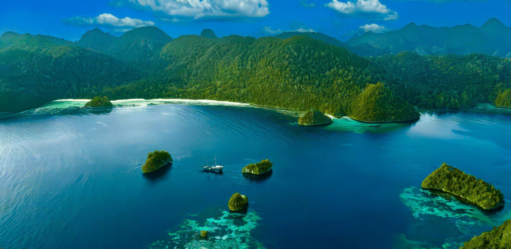 Aerial view of a serene bay within the stunning Raja Ampat, where small islands are surrounded by clear blue water and lush green hills, offering an ideal spot for exploring. A lone sailing boat navigates this vibrant piece of the Coral Triangle.