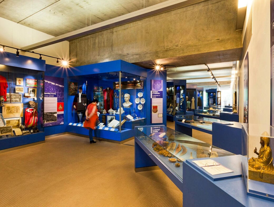 A person observes exhibits in a well-lit museum room featuring blue display cases filled with historical artifacts, documents, and clothing—one of the top Cork attractions for visitors seeking memorable Things to Do in Cork.
